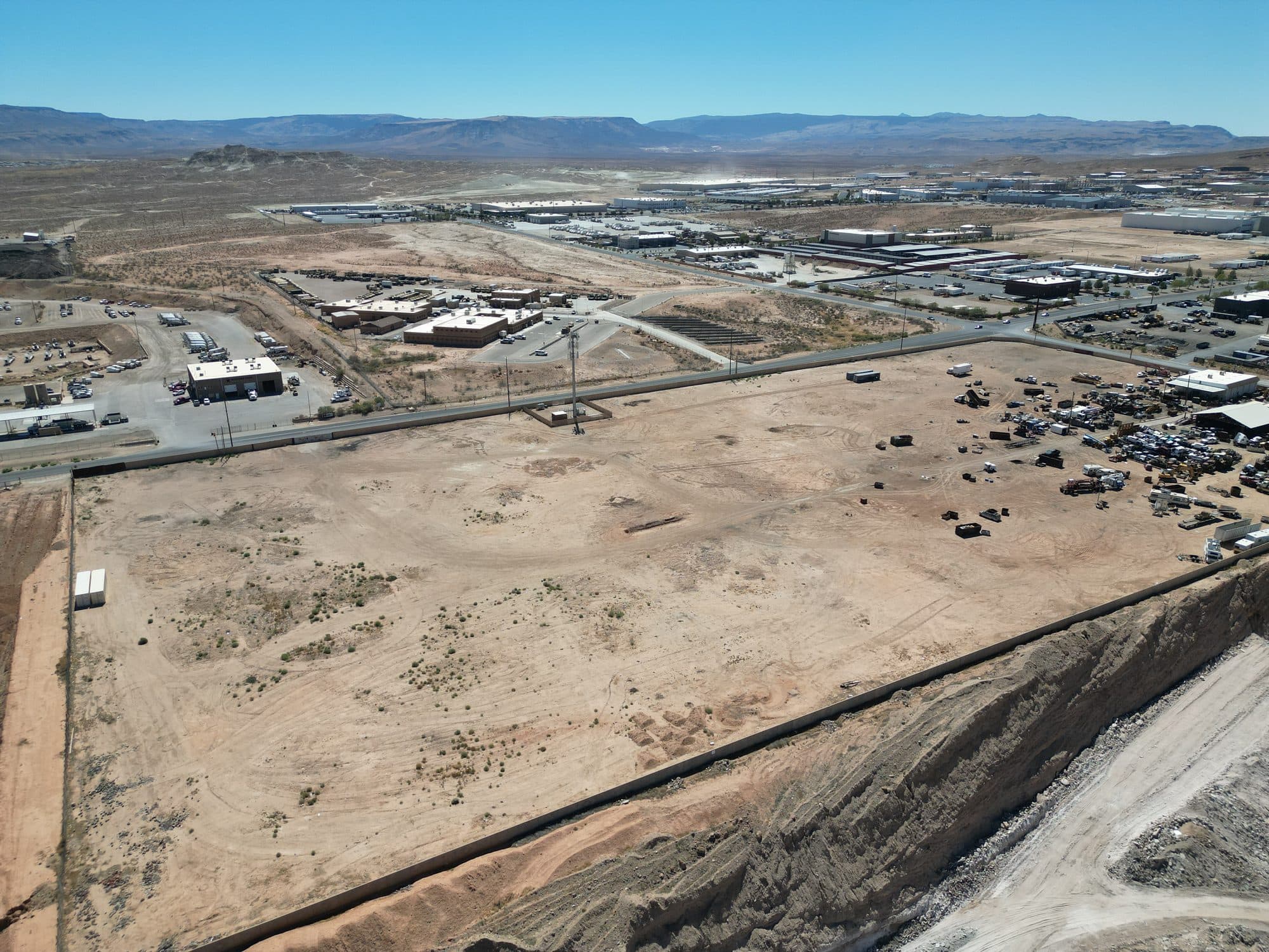 Aerial view over the parcel toward the surrounding industrial area and distant mountains